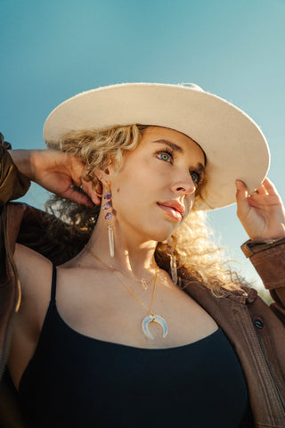 Woman wearing turquoise and amethyst drop earrings earrings