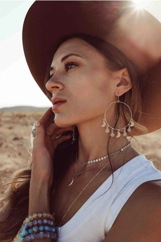 Woman in the desert wearing moonstone earrings and a moonstone bracelet.
