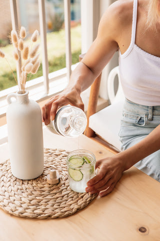 Woman in the morning light drinking cucumber water